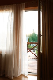 Photo of Open balcony door with curtain in apartment