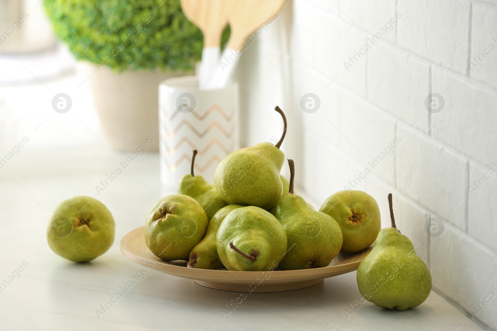 Photo of Fresh ripe pears on white countertop in kitchen