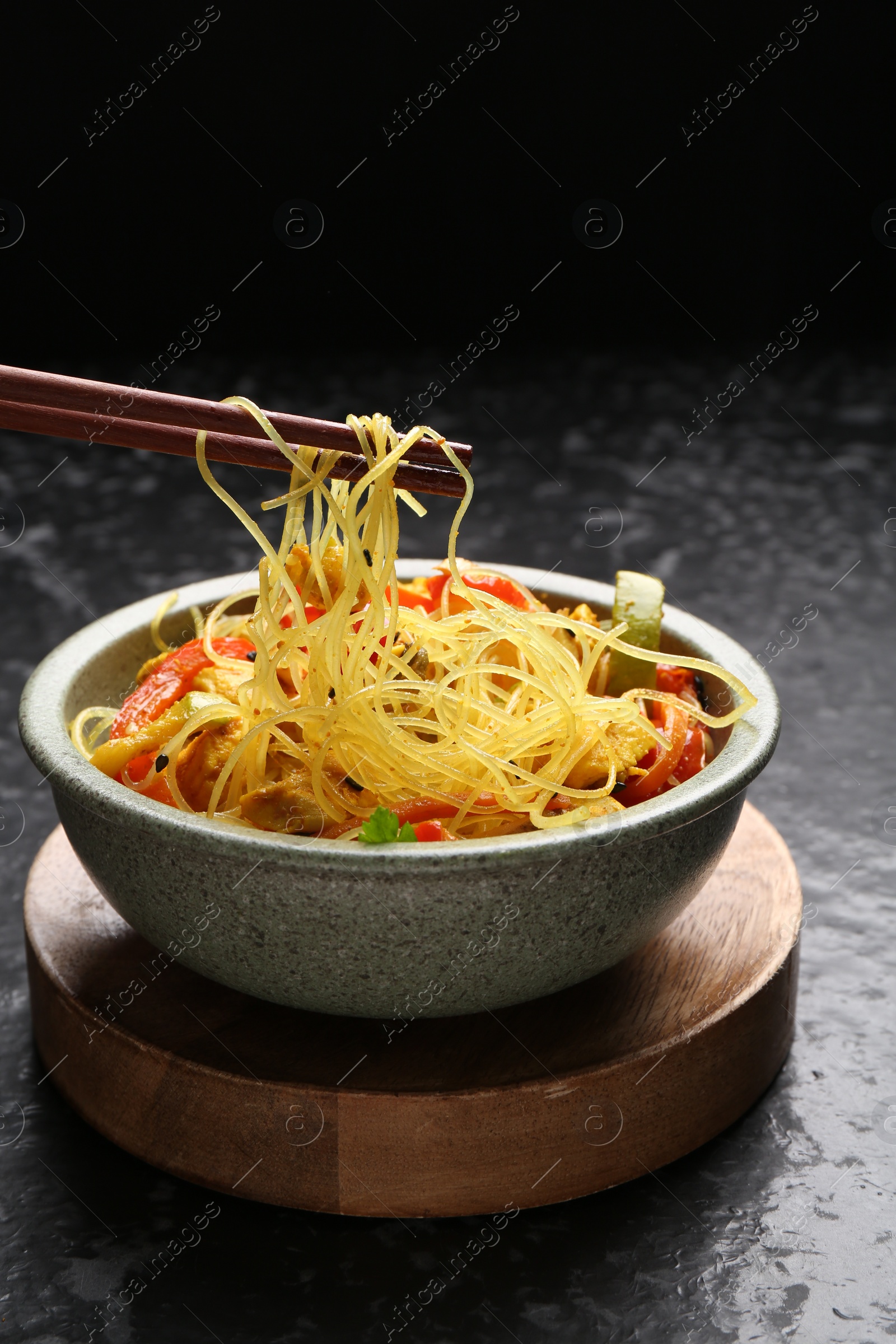 Photo of Stir-fry. Eating tasty noodles with meat and vegetables at dark textured table