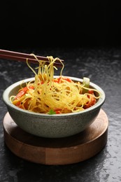 Photo of Stir-fry. Eating tasty noodles with meat and vegetables at dark textured table