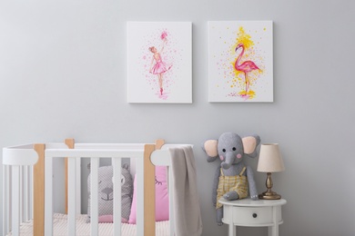 Photo of Children's room with comfortable crib and pictures on grey wall. Interior design