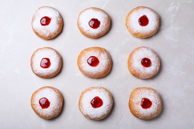 Hanukkah doughnuts with jelly and sugar powder on grey table, flat lay