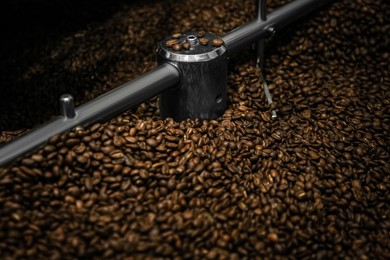 Photo of Modern coffee roaster machine with beans, closeup