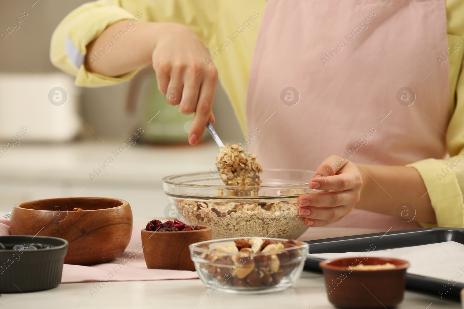 Photo of Woman making granola at table in kitchen, closeup