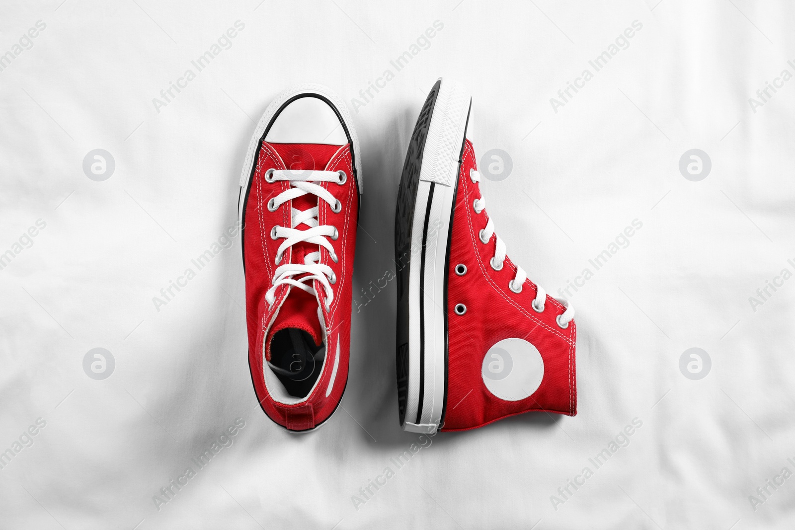 Photo of Pair of new stylish red sneakers on white fabric, flat lay