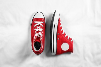 Pair of new stylish red sneakers on white fabric, flat lay