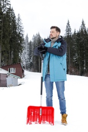 Man with shovel for snow removal near house