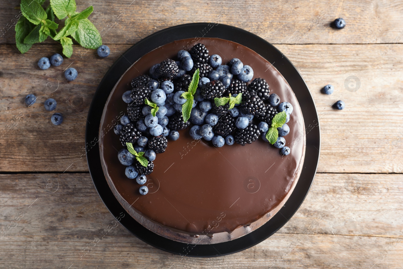 Photo of Fresh delicious homemade chocolate cake with berries on wooden table, top view