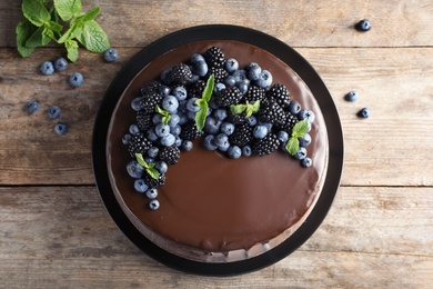 Photo of Fresh delicious homemade chocolate cake with berries on wooden table, top view