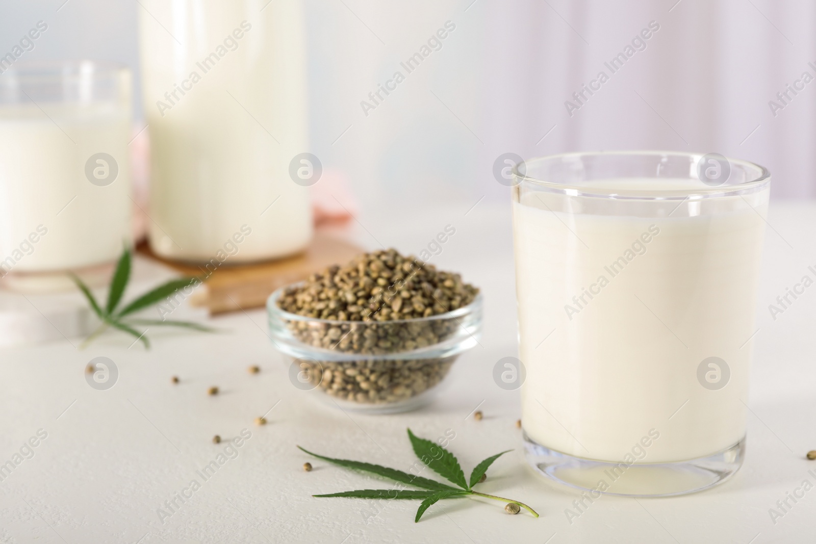 Photo of Composition with glass of hemp milk on white table indoors