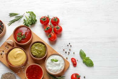 Flat lay composition with different sauces and space for text on white wooden background