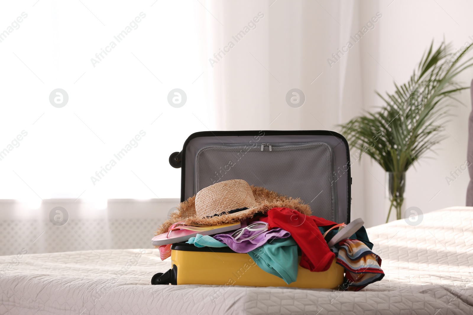 Photo of Modern suitcase full of clothes on bed indoors. Space for text