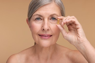 Photo of Beautiful woman with vitamin capsule on beige background