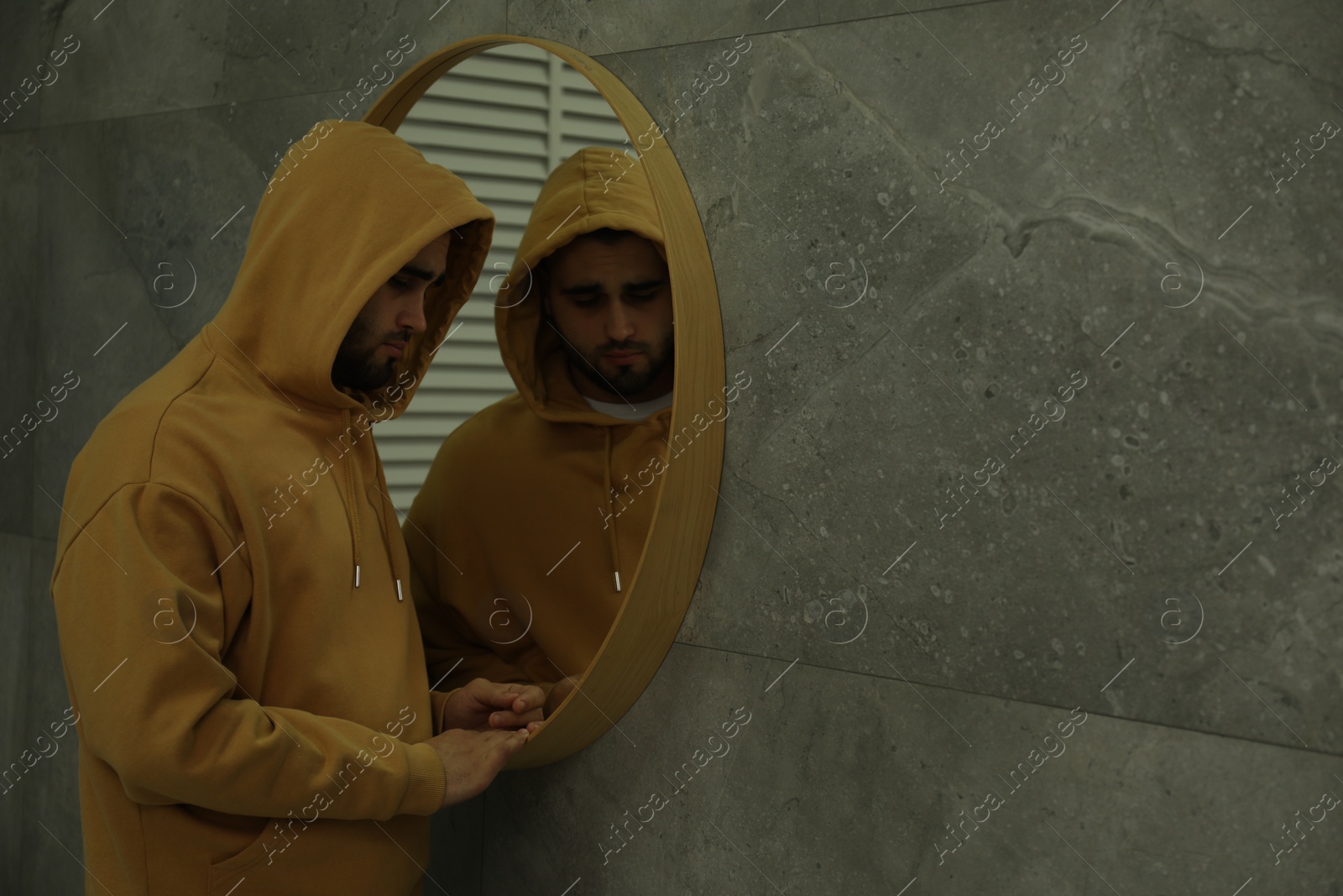 Photo of Sad man near mirror at home. Space for text