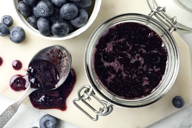 Photo of Jar of blueberry jam and fresh berries on table, top view
