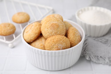 Photo of Tasty sugar cookies in bowl on white tiled table, closeup