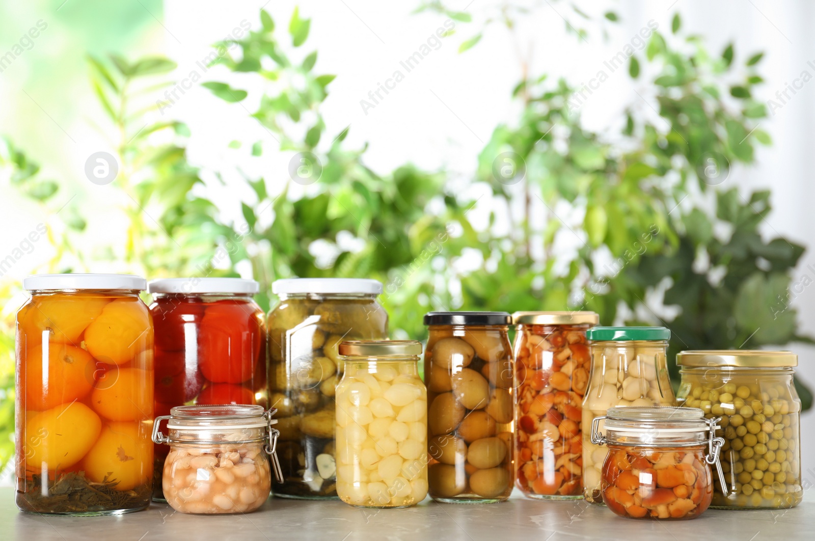 Photo of Glass jars of different pickled vegetables on marble table