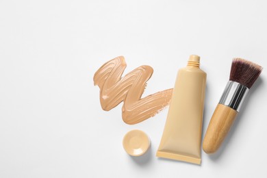 Photo of Liquid foundation, makeup brush and swatch on white background, flat lay. Space for text