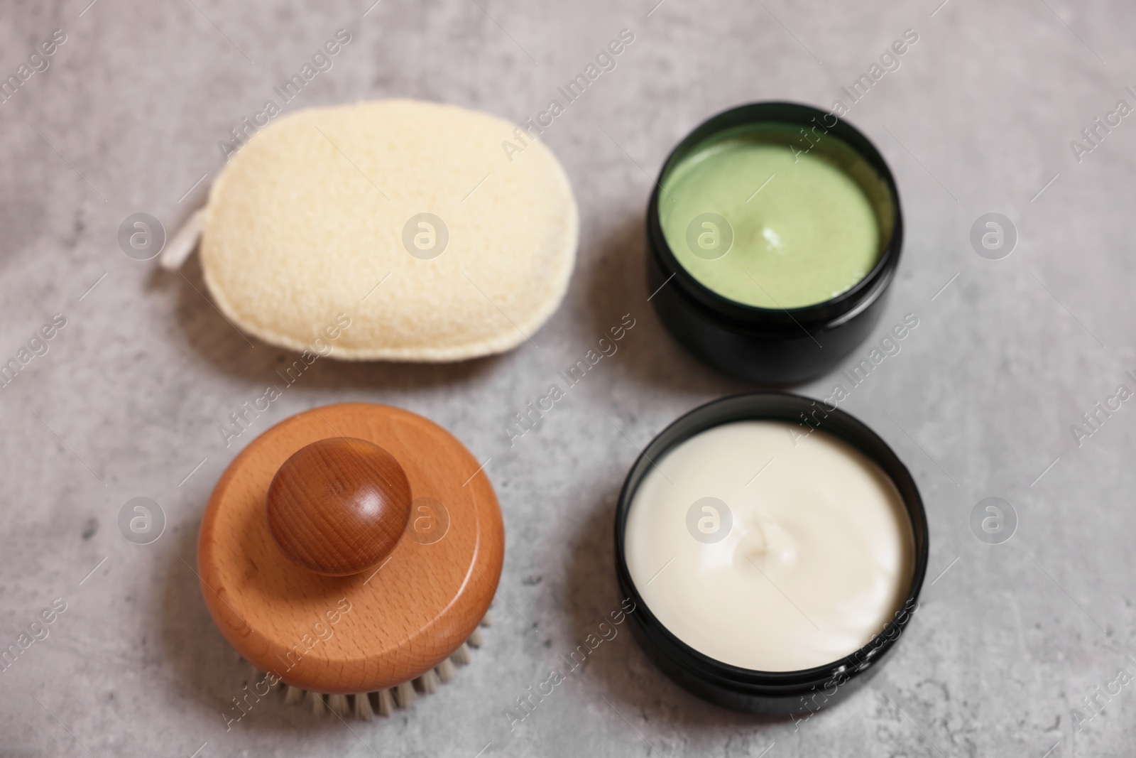 Photo of Natural body scrub, cream, brush and sponge on grey table