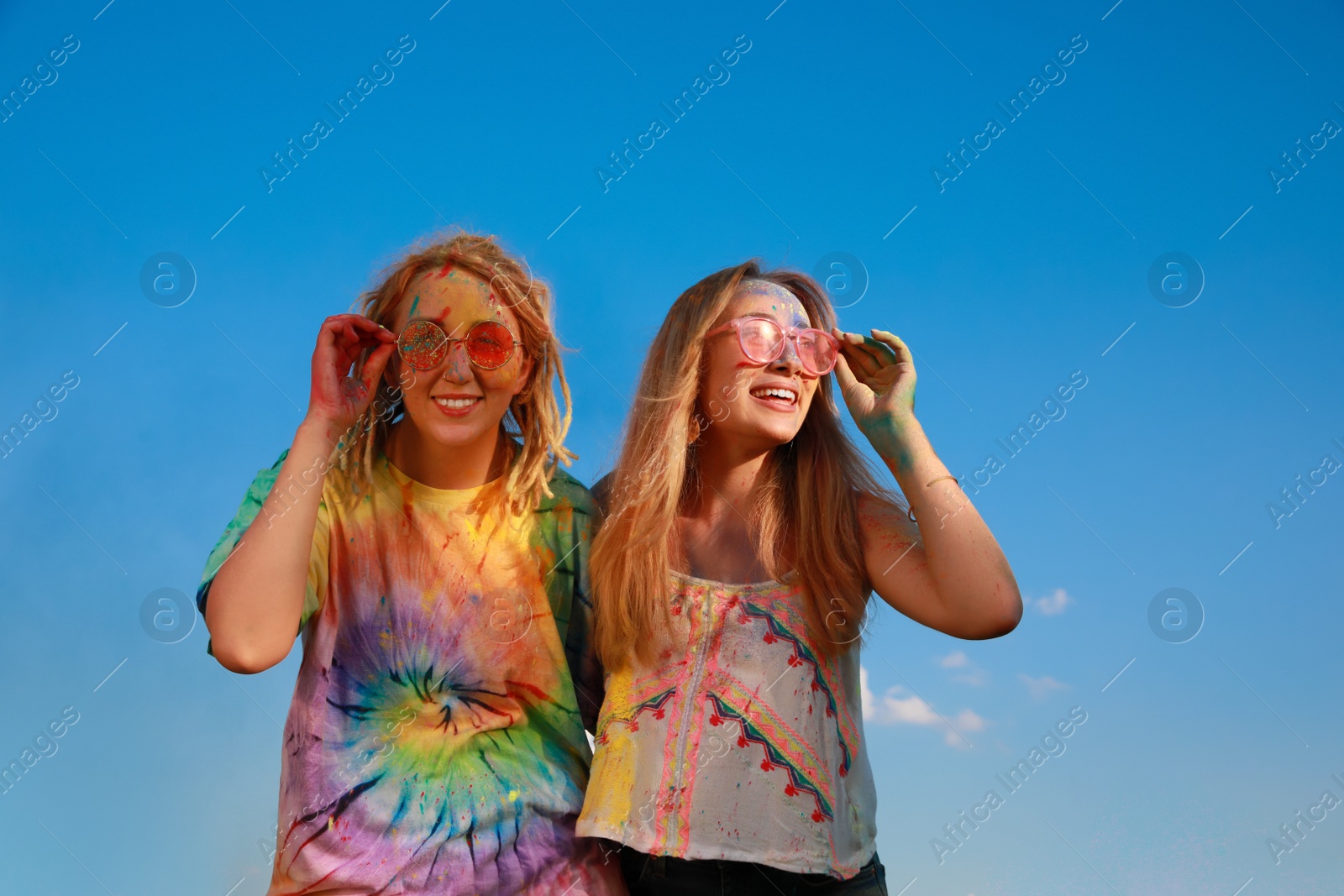 Photo of Happy women covered with colorful powder dyes outdoors. Holi festival celebration