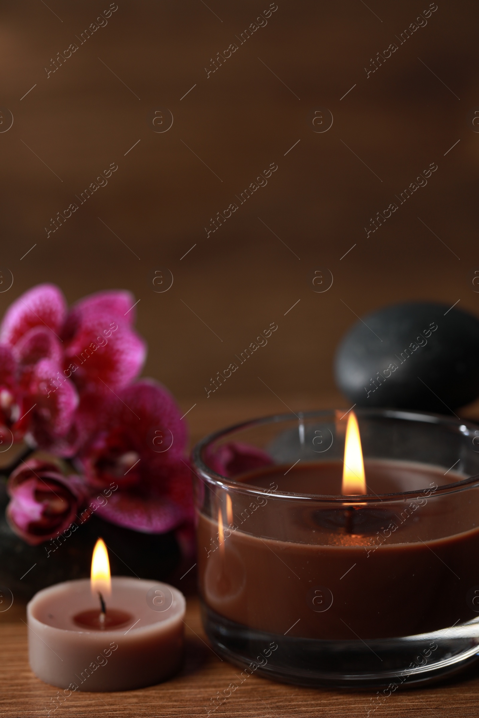 Photo of Beautiful spa composition with burning candles and flowers on wooden table