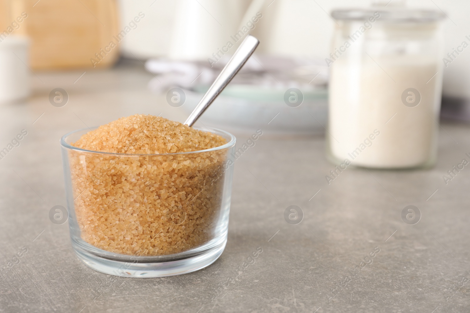 Photo of Glass bowl with brown sugar on grey table