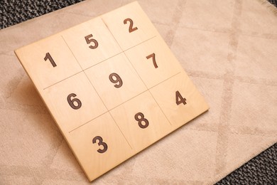 Photo of Wooden board with numbers on beige rug indoors. Montessori toy
