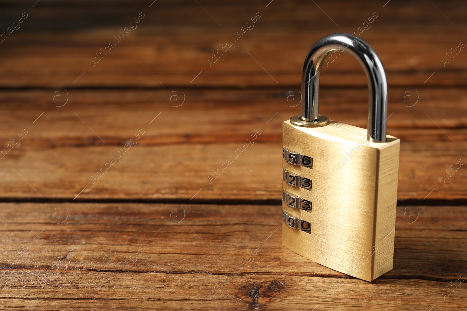 Photo of One steel combination padlock on wooden table, closeup. Space for text