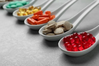 Photo of Spoons with different dietary supplements on light grey table, closeup. Space for text