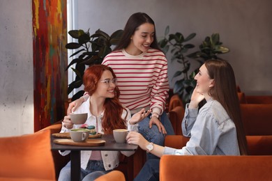 Photo of Happy friends talking and drinking coffee in cafe