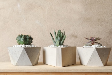 Beautiful succulent plants in stylish flowerpots on wooden table against brown background. Home decor