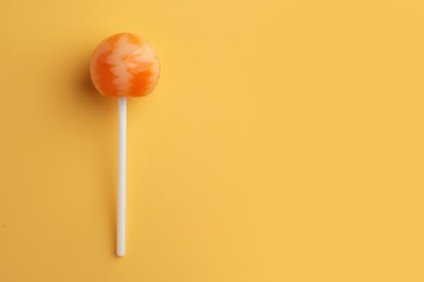 Tasty lollipop on orange background, top view. Space for text