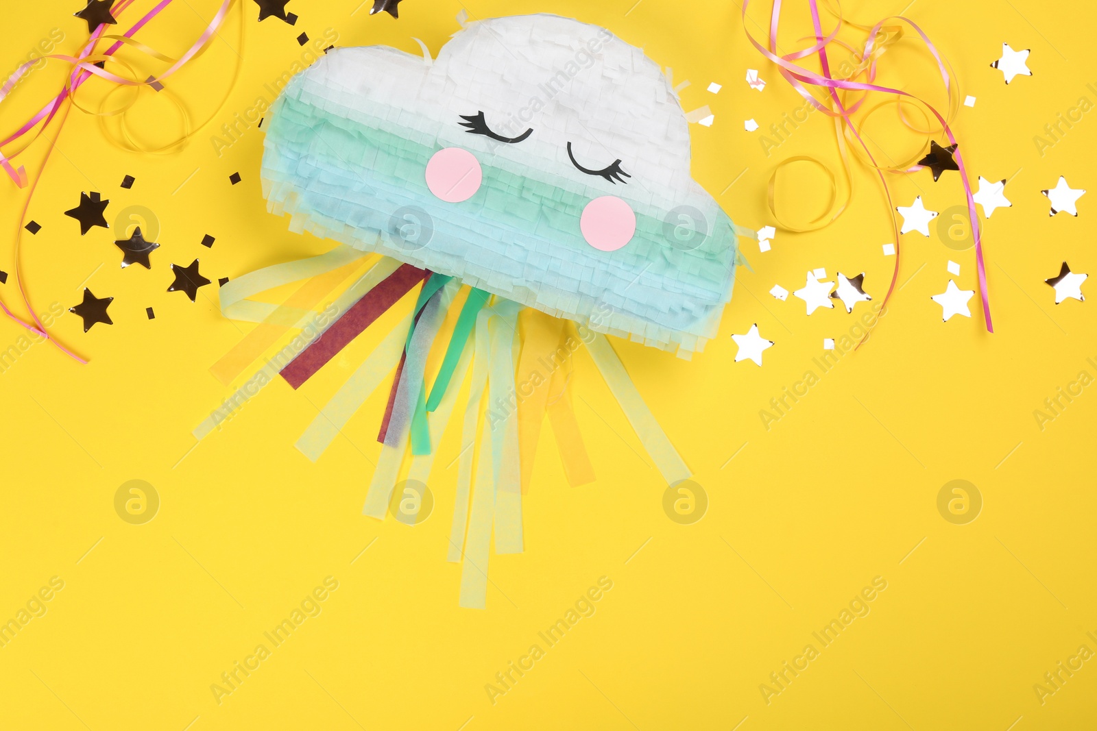 Photo of Bright cloud pinata and confetti on yellow background, flat lay. Space for text