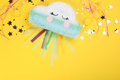 Photo of Bright cloud pinata and confetti on yellow background, flat lay. Space for text