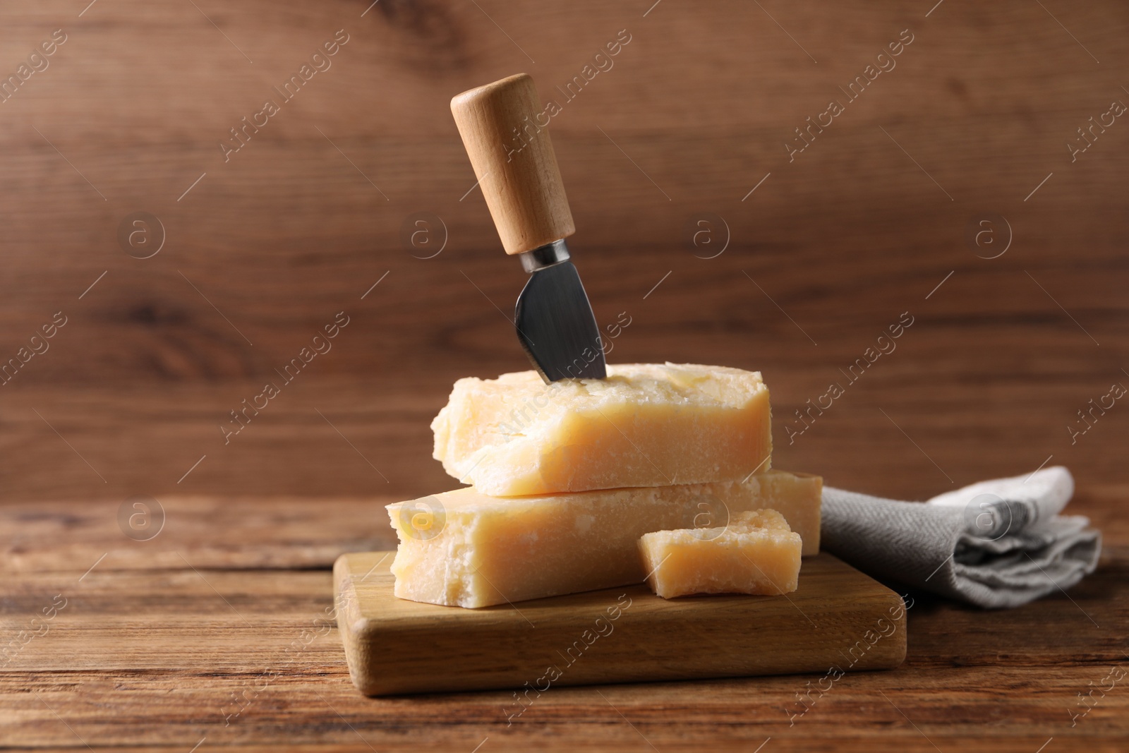 Photo of Delicious parmesan cheese with knife on wooden table