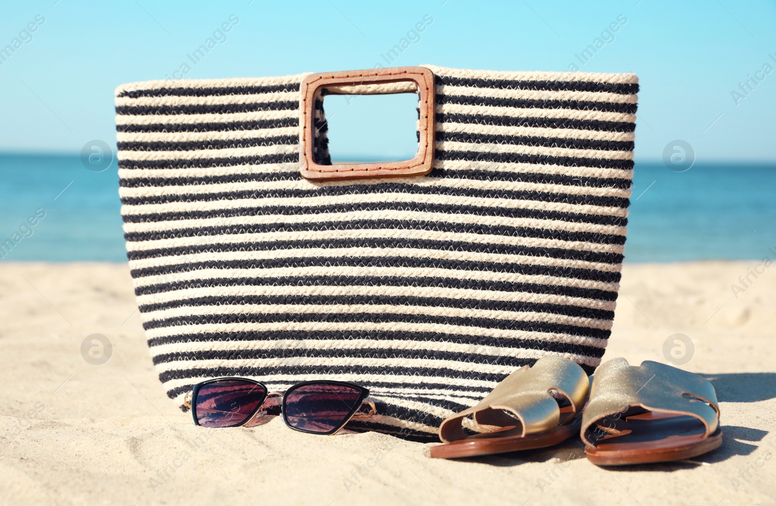 Photo of Stylish beach accessories on sandy sea shore