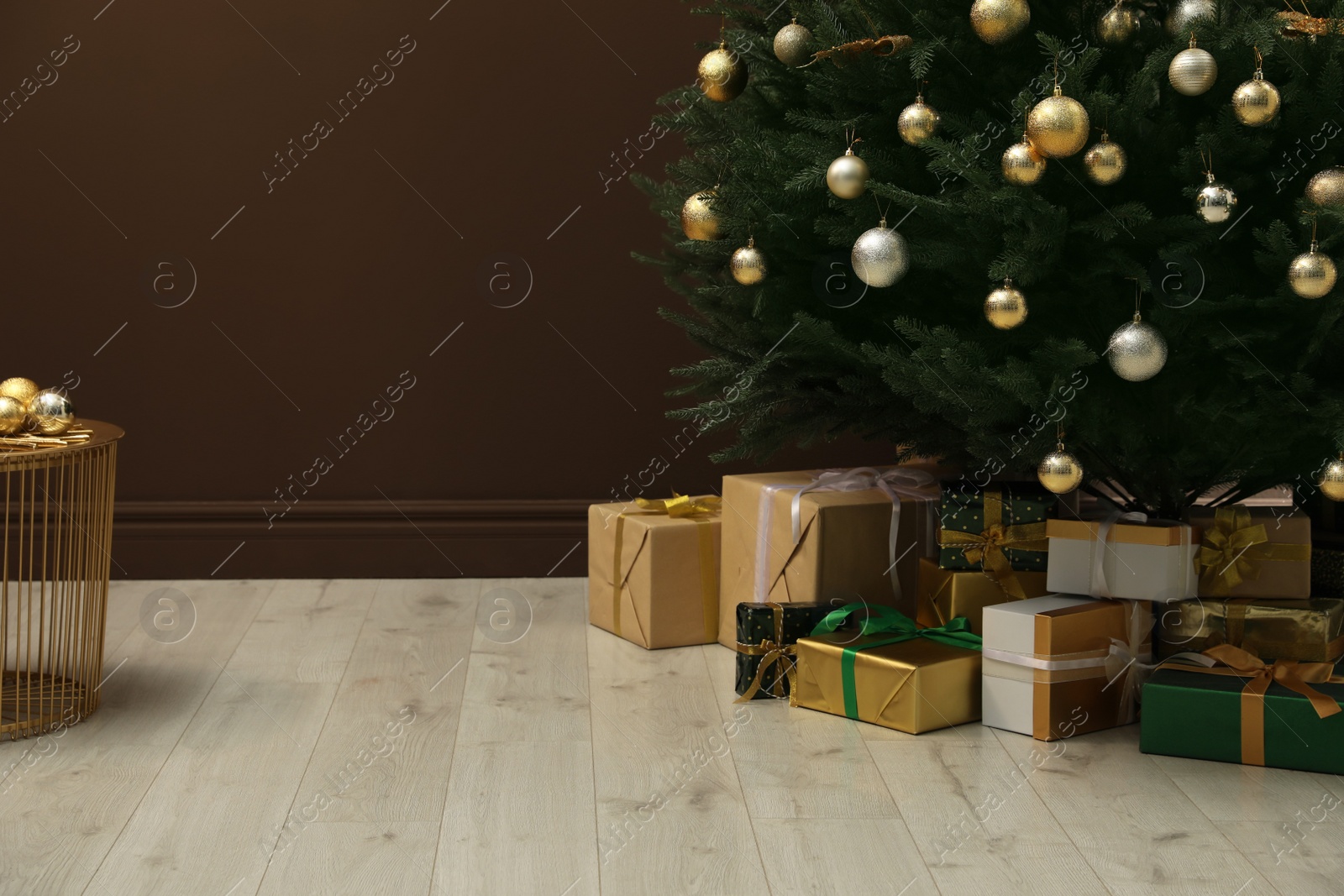 Photo of Beautifully decorated Christmas tree and many gift boxes near brown wall indoors, space for text