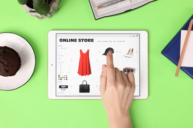 Photo of Woman with tablet shopping online on green background, top view