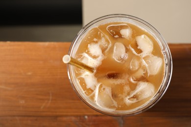 Refreshing iced coffee with milk in takeaway cup on wooden table, top view. Space for text