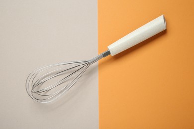 Photo of Metal whisk on color background, top view