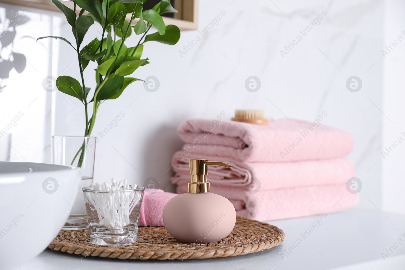 Photo of Dispenser and cotton swabs on countertop in bathroom