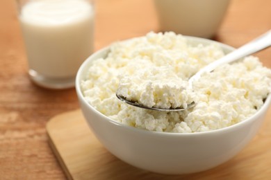 Delicious fresh cottage cheese in bowl on wooden table, closeup