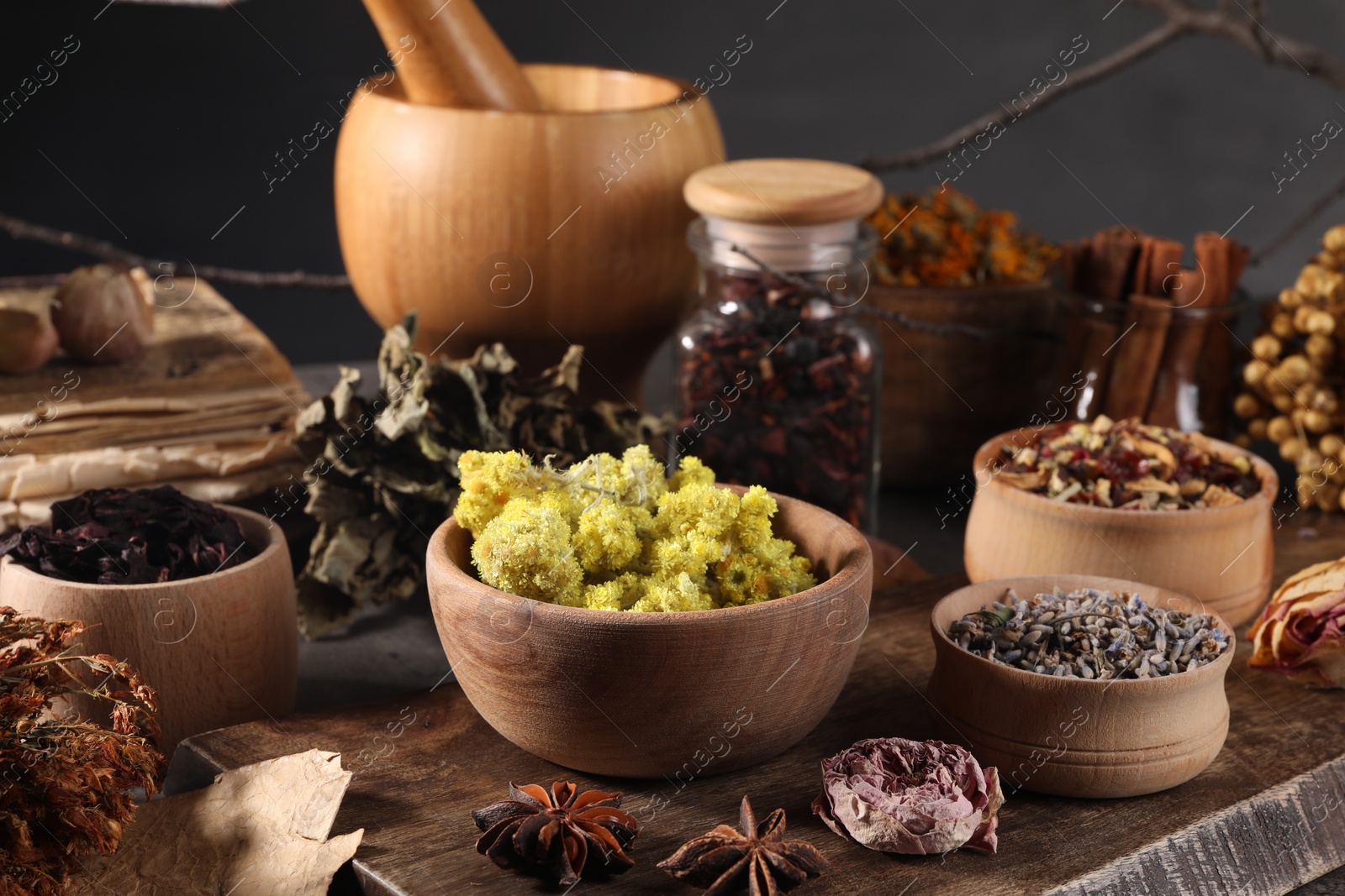 Photo of Many different dry herbs, flowers and mortar with pestle on table