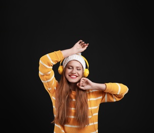 Photo of Young woman listening to music with headphones on black background