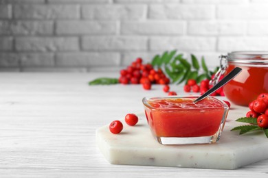 Photo of Delicious rowan jam in glass bowl on white wooden table. Space for text