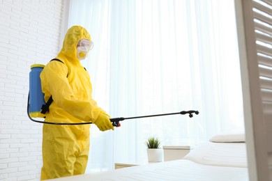 Photo of Employee in protective suit sanitizing doctor's office. Medical disinfection