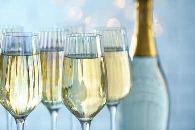 Photo of Glasses and bottle of champagne against blurred lights, closeup