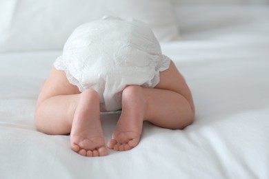 Cute little baby in diaper on bed