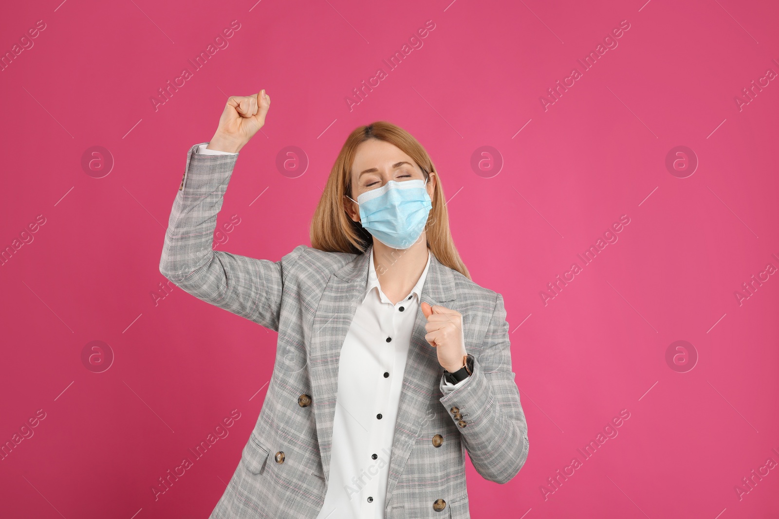 Photo of Emotional businesswoman with protective mask on pink background. Strong immunity concept