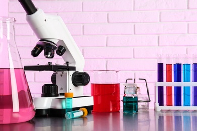 Photo of Different glassware with samples and microscope on table in chemistry laboratory